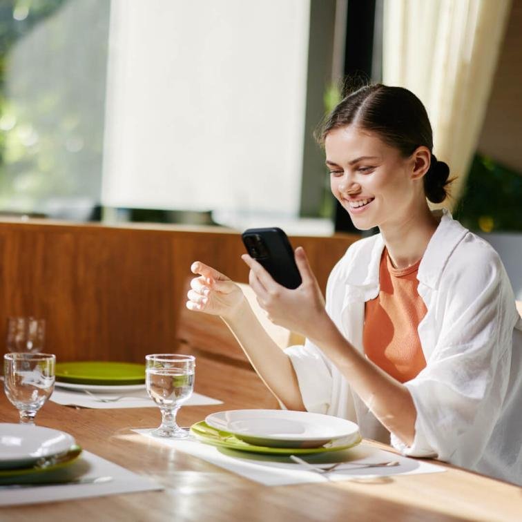 lady looking at the phone while at the dining table